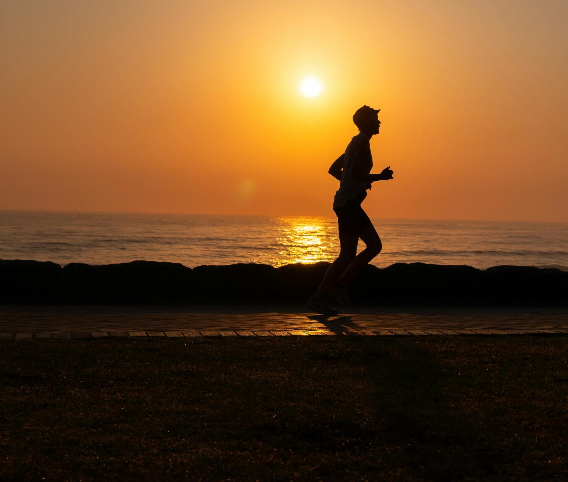 Runner che corre al tramonto sul mare durante un allenamento